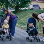 a woman pushing a stroller with two children in it