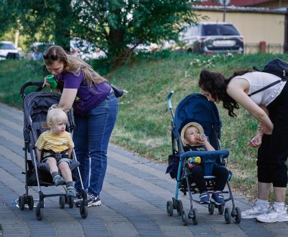 a woman pushing a stroller with two children in it